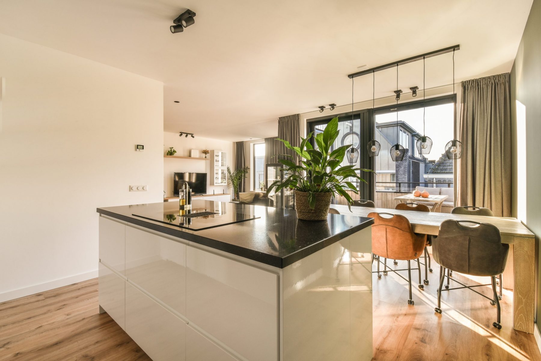 a kitchen and dining area in a house with wood floors, white cabinets, black counter tops and wooden flooring