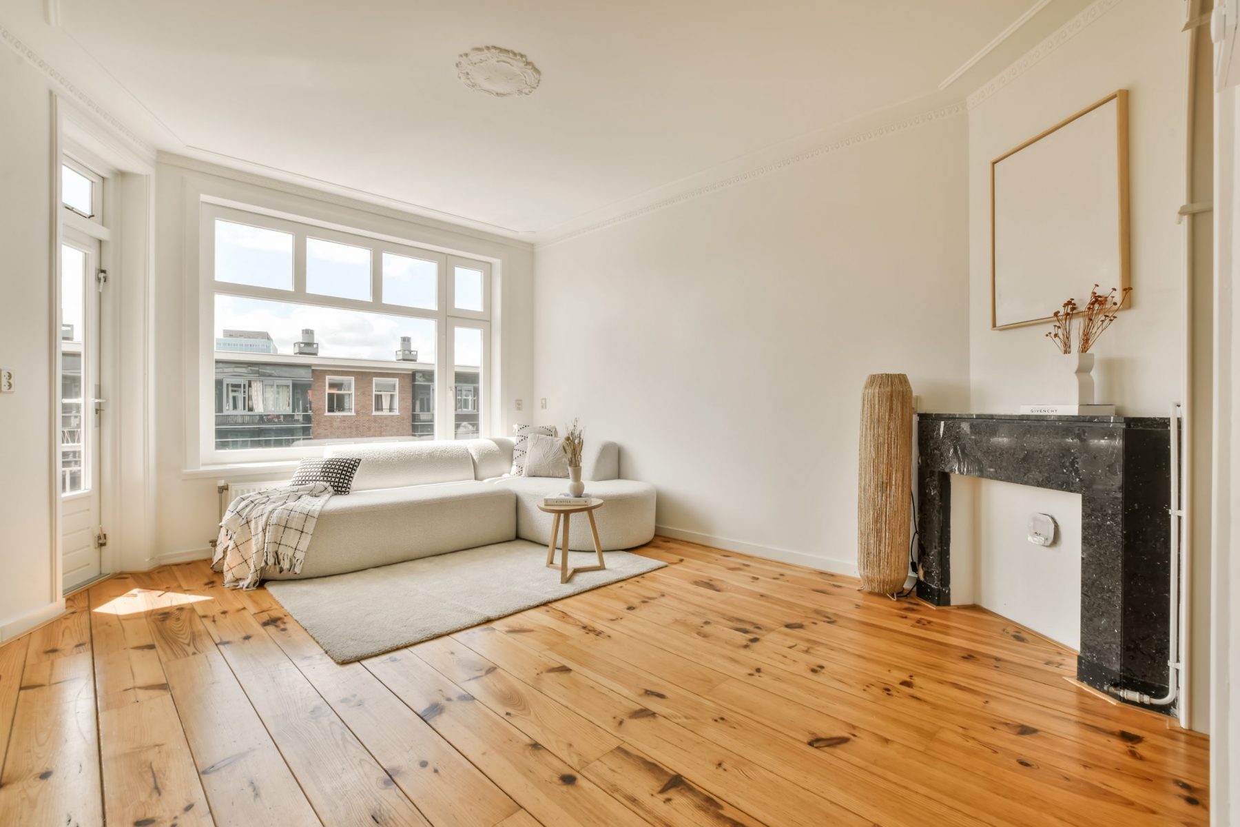 a living room with wood flooring and white walls, including a large window looking out to the city below